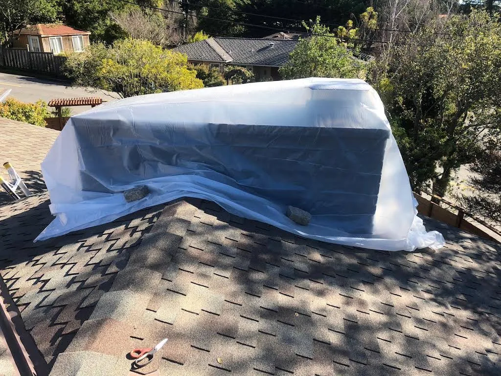 Residential chimney wrapped to protect the roof during repair preparation