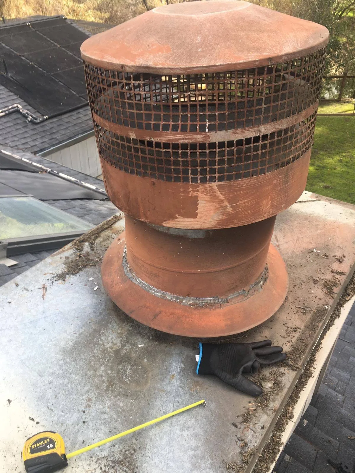 Weathered metal chimney cap documented during a rooftop chimney service visit